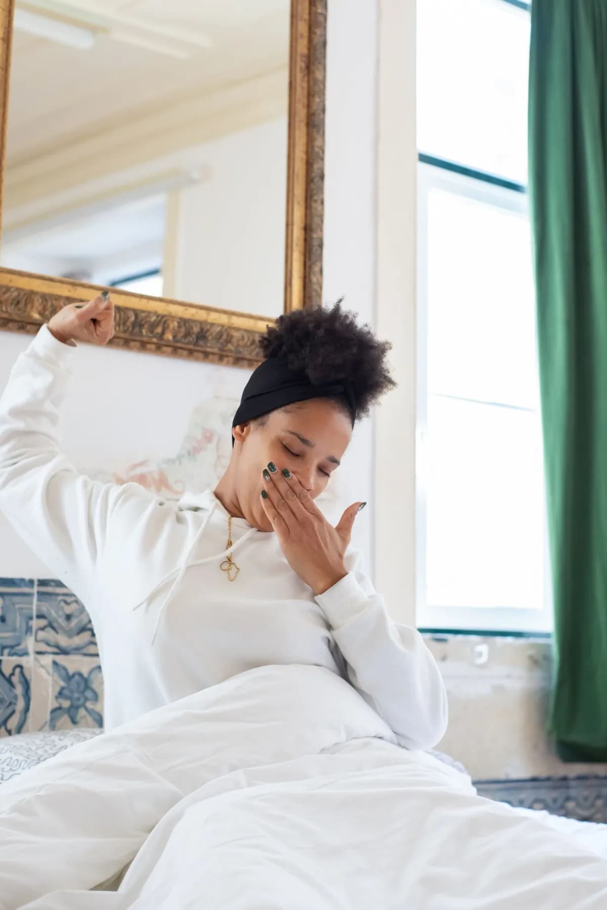 A woman stretching as she wakes in a bright bedroom